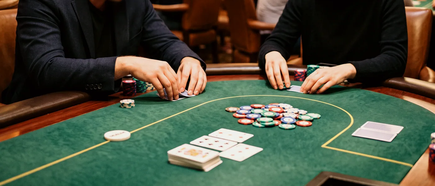 A house dealer fanning a fresh deck across green baize before a hand of five hundred begins.